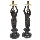 A pair of bronze candelabra in the form of Classical maidens holding aloft brass sconces,