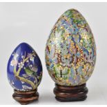 Two early 20th century cloisonné eggs on stands, height of largest 25cm (2).