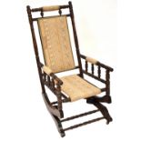 An American walnut turned rocking chair upholstered with a woven cream material with diamond and