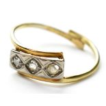 An 18ct gold three stone diamond ring, the three small diamonds gypsy set in a row of white gold,