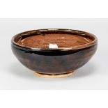 URSULA MOMMENS (1908-2010); a stoneware bowl covered in tenmoku breaking to kaki glaze, impressed UD