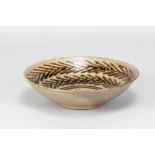 HELEN PINCOMBE (1908-2004); a shallow stoneware footed bowl with tenmoku breaking to kaki decoration