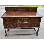 A 1920s Jacobean style oak dresser, with raised back above two central doors flanked by cupboard