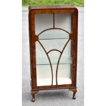 An Art Deco burr walnut veneered display cabinet, the single glazed door enclosing two fixed