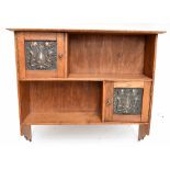 An Arts & Crafts light oak hanging shelf, with two cupboard doors inset with embossed copper
