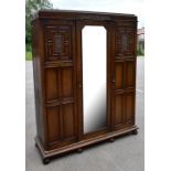 An early 20th century oak triple door wardrobe, the central door with bevelled mirror plate, flanked