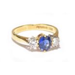 An 18ct yellow gold three stone diamond and sapphire ring, the sapphire flanked by two 0.15diamonds,