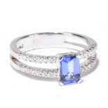 An 18ct white gold tanzanite and diamond ring, the central emerald cut tanzanite set with thirty-two