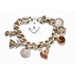 A silver curb link charm bracelet suspending various charms including claw and glass ball example,