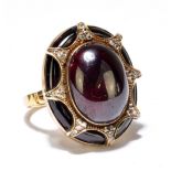 An 18ct yellow gold garnet and diamond ring, the large oval cabochon set within a framework of