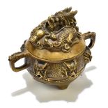 A Chinese bronze censer and cover, the lid cast with a recumbent dragon, the base cast with six mask