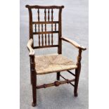 A 19th century rush seated spindle back chair, raised on turned column supports terminating on pad