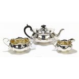RF MOSLEY; a George V hallmarked silver three piece tea set of shaped oval form, with gilded