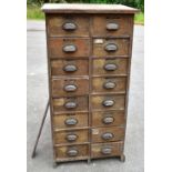 An Edwardian oak bank of sixteen short drawers, each with cusped handles, enclosing various tools