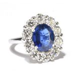 An 18ct white gold diamond and sapphire cluster ring, the central oval cut sapphire weighing