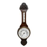 An early 20th century carved oak aneroid barometer with circular dial below a thermometer, height