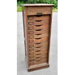 An early 20th century pillar music cabinet, with tambour enclosing twelve drawers, on plinth base,