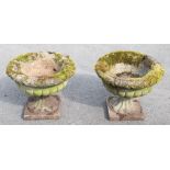 A pair of reconstituted stone garden urns on stands, with demi-fluted detailing, height 39cm,