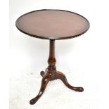 A George III mahogany tilt top occasional table raised on turned baluster column and terminating