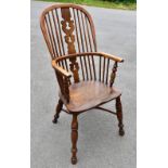 An 18th century ash and elm Windsor armchair, with crinoline stretcher, raised on turned column