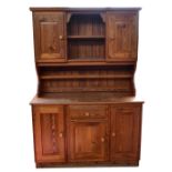 A modern pitch pine dresser, the high back with two panelled cupboard doors above central fixed