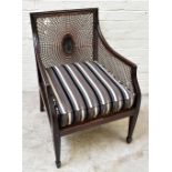 An Edwardian mahogany Regency design bergère library chair with single caned back, seat and arms, on