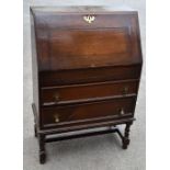 An early 20th century oak bureau, the fall front enclosing five pigeon holes above a secret drawer