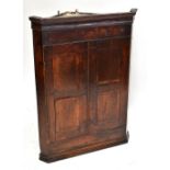 A Georgian oak corner cupboard, the twin doors enclosing two shelves, height 97.5cm, width 73cm,