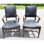 A pair of Arts and Crafts oak framed open sided armchairs, upholstered in a black vinyl material,