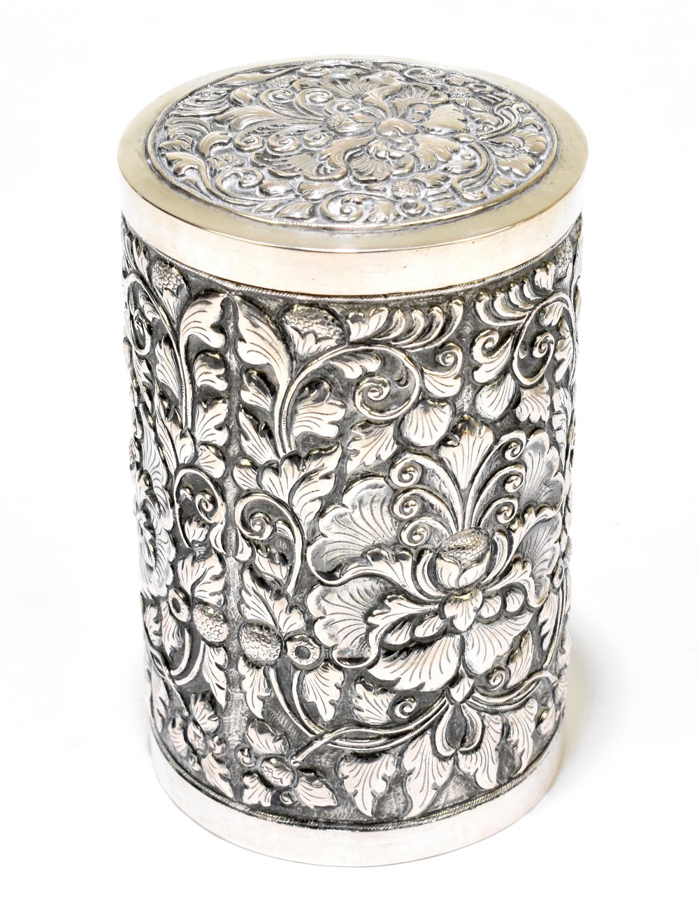 A white metal cylindrical tea canister with pull-off lid and foliate detail to the body, stamped