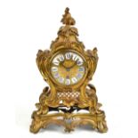 A French 19th century gilt metal mantel clock in a rococo style, the circular face with applied