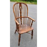 An 18th century elm and ash Windsor elbow chair, with crinoline stretcher, raised on turned column