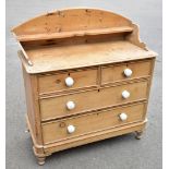 A Victorian pine chest of two short and two long drawers, with raised and arched back, on turned