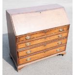 A Georgian oak bureau with fall enclosing a fitted interior, over four graduated long drawers, on