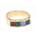 A yellow metal gem set ring with four square cut coloured stones in a channel setting, size P 1/2,