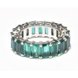 A white metal and synthetic emerald full eternity ring, size F 1/2, approx. 3.6g.Additional