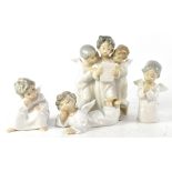 Four Lladró figurines comprising a group of three choristers, and three single angels,