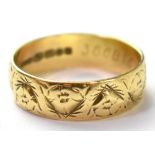 An 18ct gold band ring with a repeating flower head pattern, size Q, approx 3.8g.