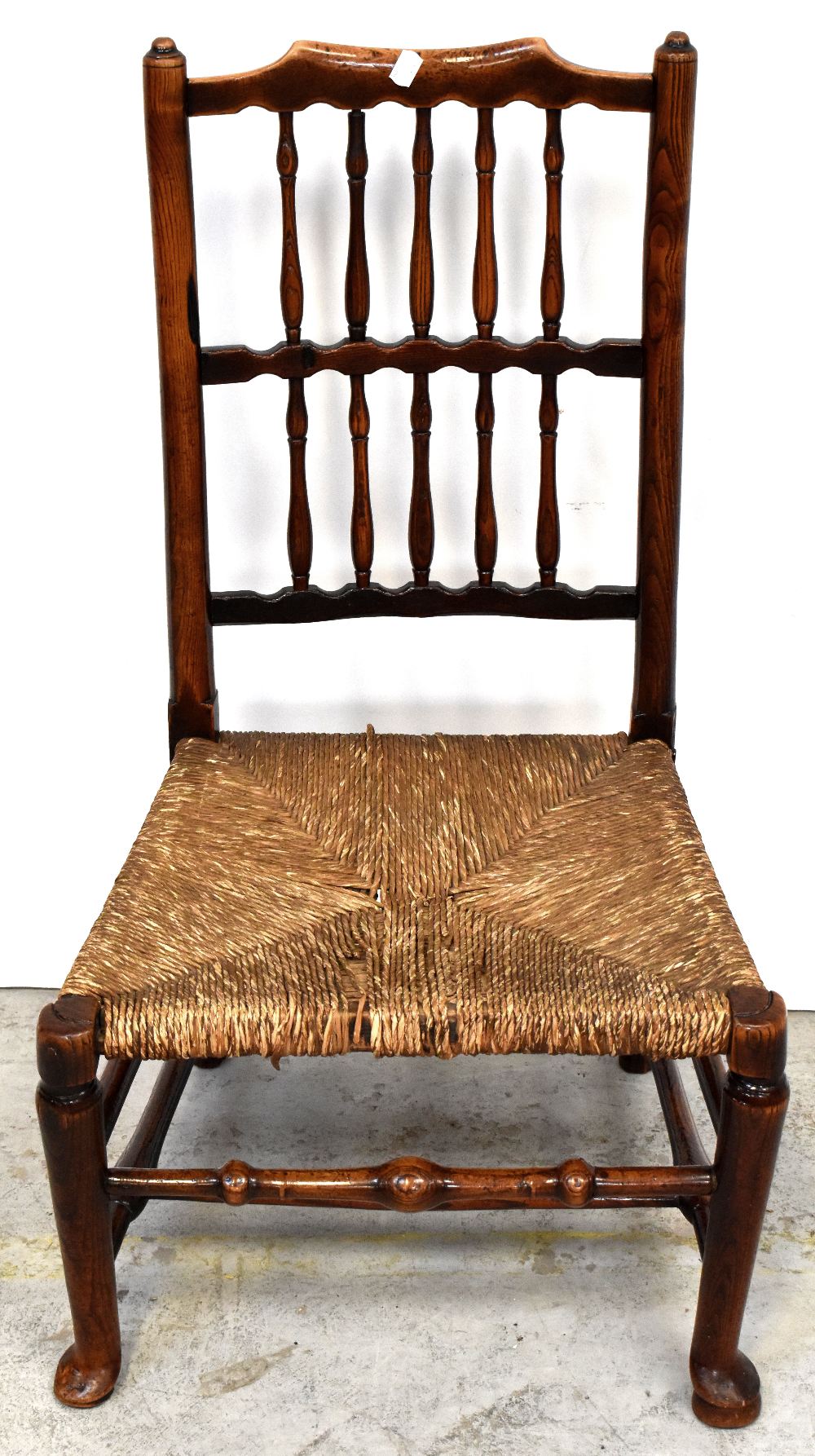 An 18th century rush seated nursing chair, the back rest with two rows of spindles,