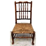 An 18th century rush seated nursing chair, the back rest with two rows of spindles,