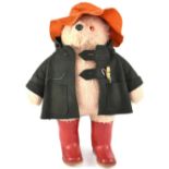 A Paddington Bear with green overcoat, orange hat and red wellingtons, length 50cm.