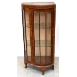 A 1940s walnut corner glazed display cabinet of shaped form,