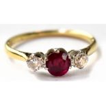 A yellow gold diamond and ruby ring, the central claw set ruby flanked by two small brilliants,