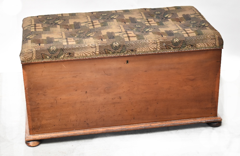 A mahogany ottoman with upholstered padded seat lid, raised on squat bun feet, 57 x 105 x 54cm.