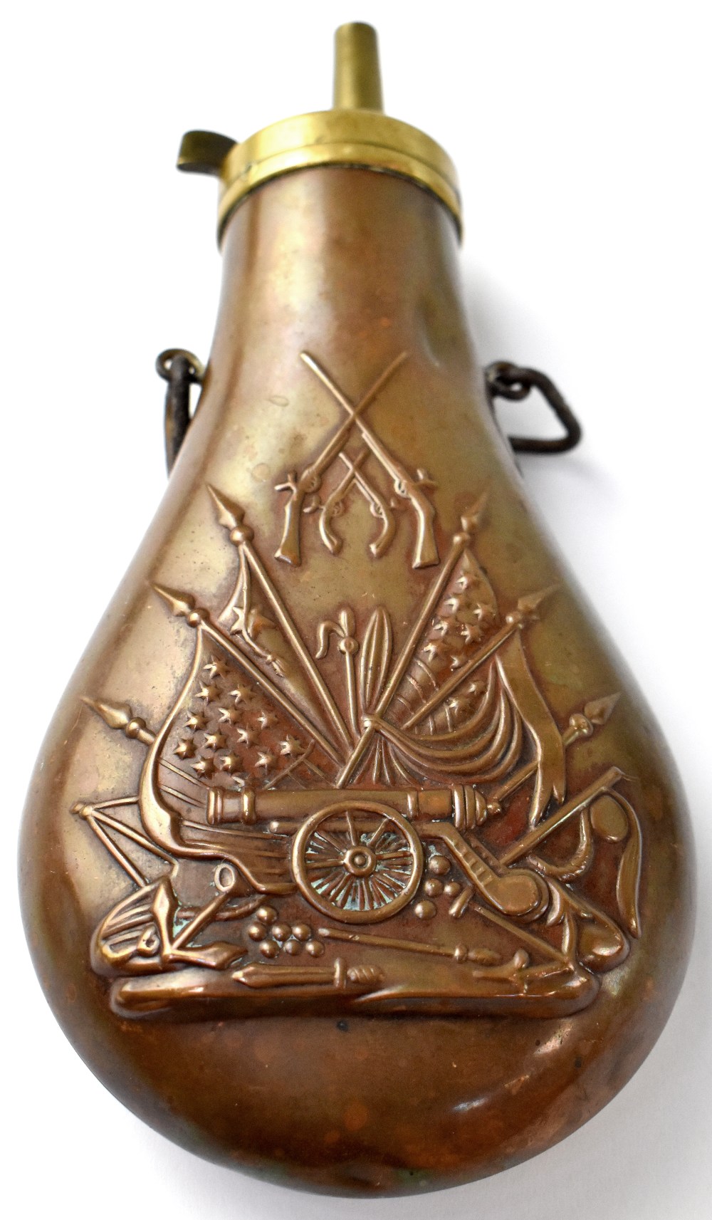 A brass and copper shot flask, embossed both sides with flags and cannon pattern,