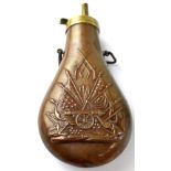 A brass and copper shot flask, embossed both sides with flags and cannon pattern,