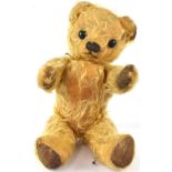 A vintage early 20th century straw-filled mohair teddy bear with large glass eyes, length 31cm.