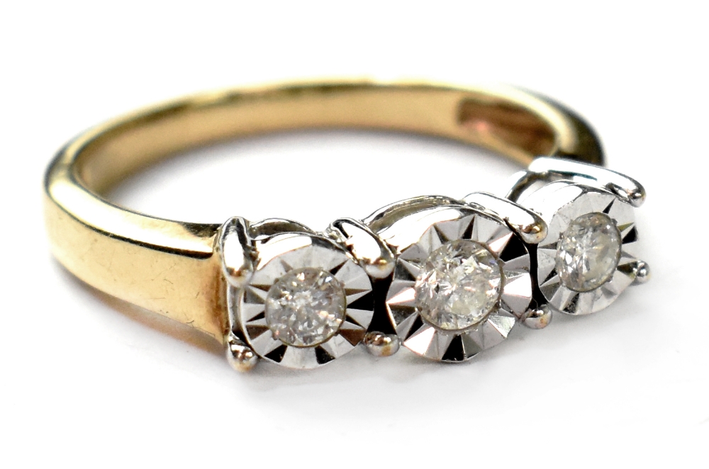 A 9ct gold three stone diamond ring, the three illusion set diamonds in a white metal gallery,