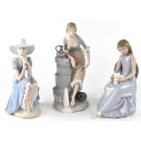Three large Nao figures to include young woman at a well, resting on rocks,