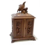 A German Black Forest carved tabletop trinket box featuring two birds above twin doors enclosing